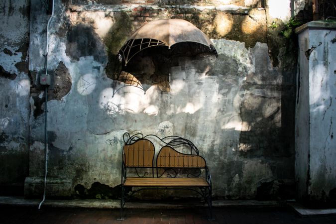 Antique brench on brick wall with  umbrella hanging on wall. Vintage brench park.
