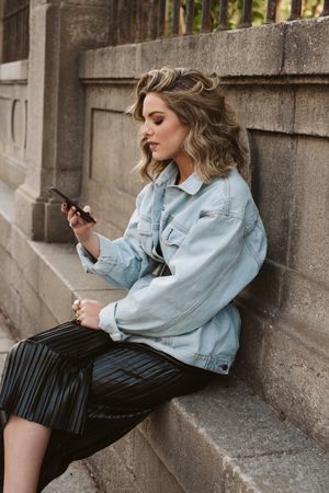 Woman using smartphone near park fence