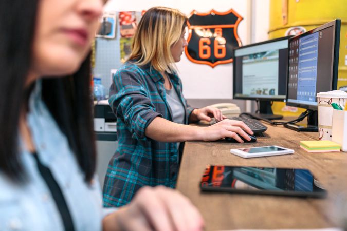 Blonde young woman checking orders in a computer received by ecommerce shop