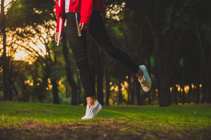 Crop woman jumping slightly above green grass