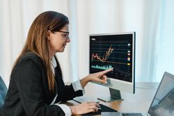 Female trader working with chart on computer monitor