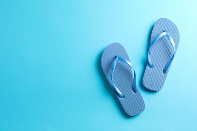 Flip flops on color background, space for text. Summer vacation backdrop