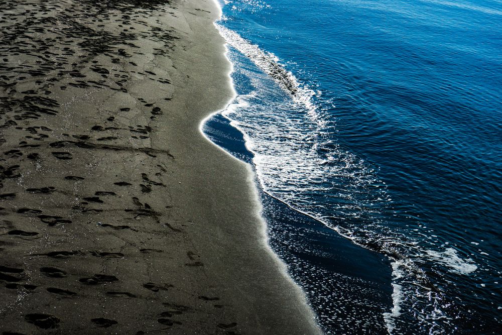 Dark volcanic sand beach and sea
