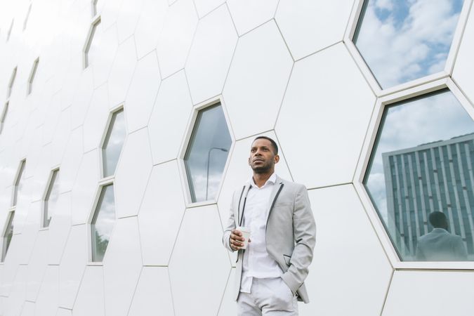 Black man with coffee standing in downtown