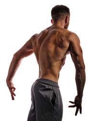 Bodybuilder turned around practicing poses ahead of competition in light studio