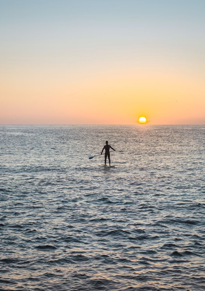 Man practicing paddle surfing with neoprene in a sunrise