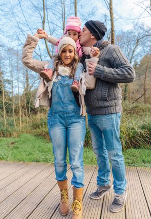 Daughter on mother's shoulders as father gives her a kiss