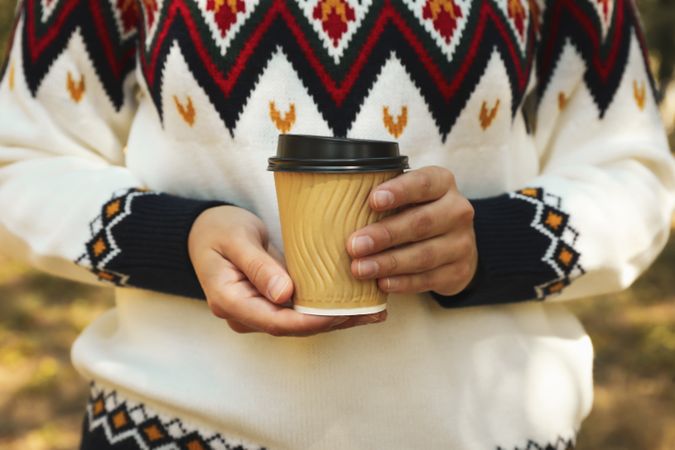 Woman in sweater hold paper cup outdoor