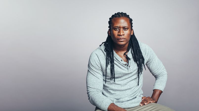 Muscular man with dreadlocks isolated on grey background