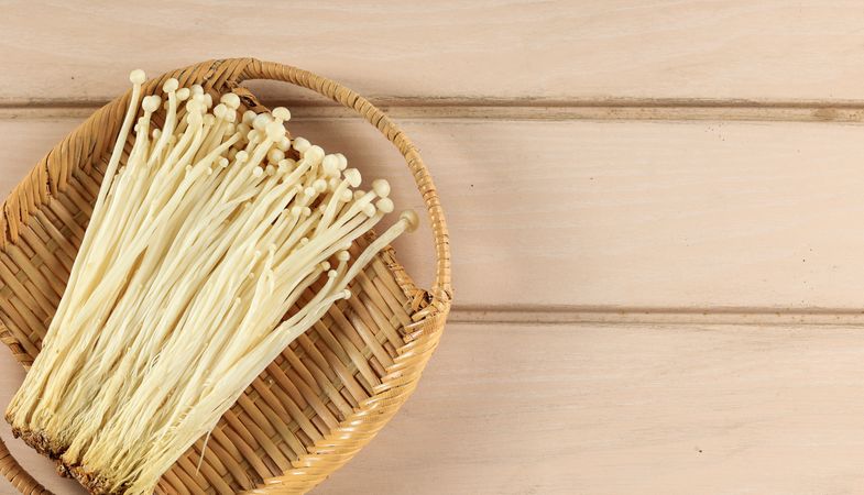 Bamboo basket of fresh golden needle mushrooms with space for text