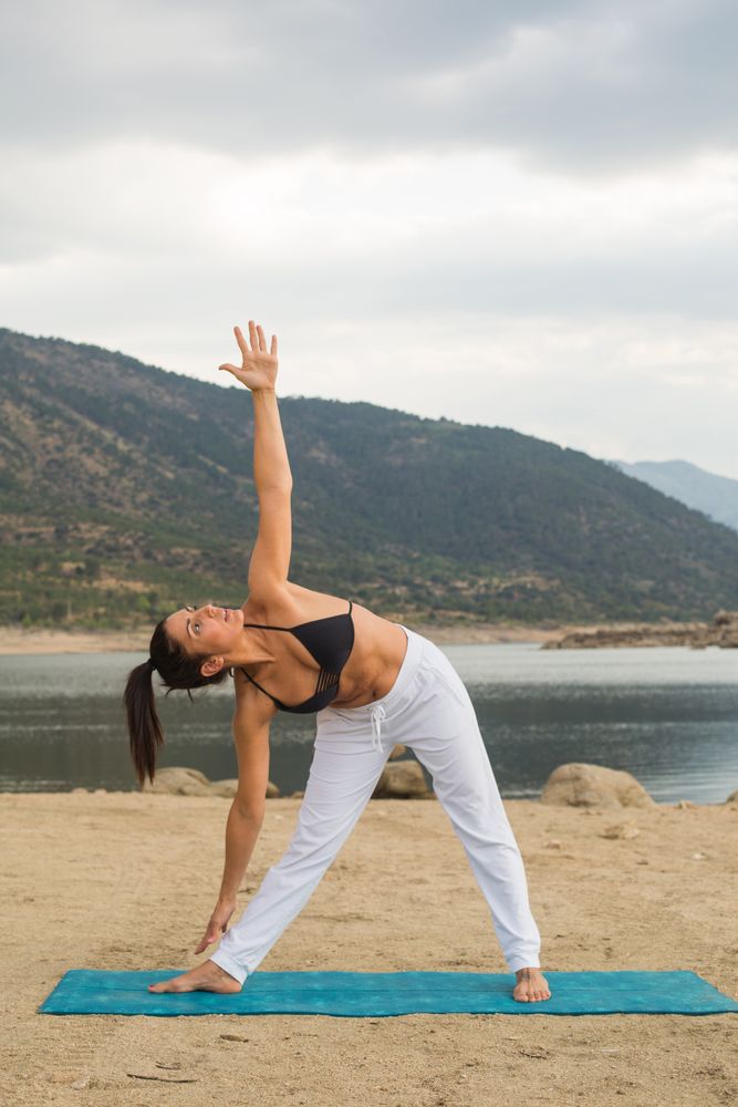 Woman practicing yoga outdoors near water