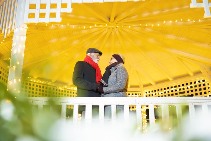 Mature man and woman standing under a gazebo on a cold day