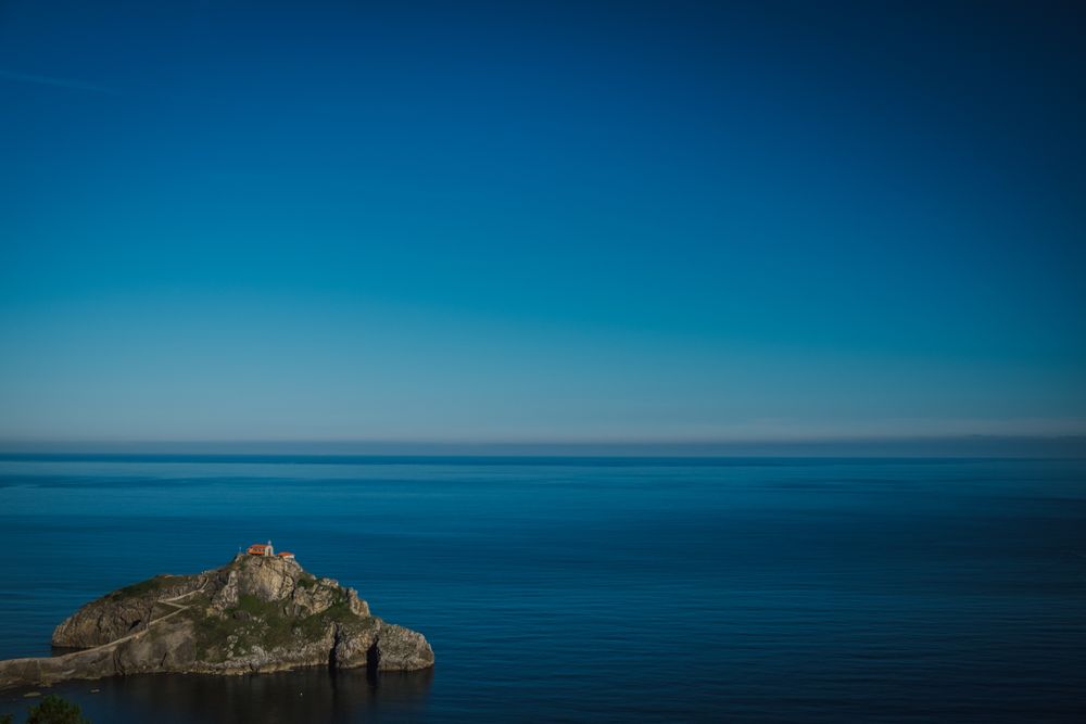 Lonely island amid sea tranquility under perfect blue sky