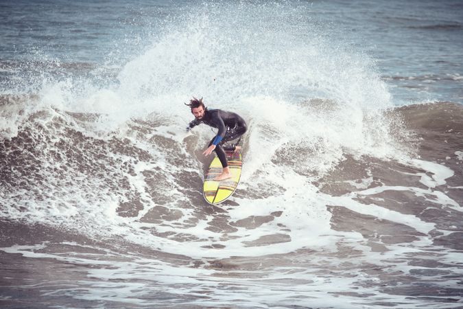 Male surfer on surfboard riding on wave in stormy sea