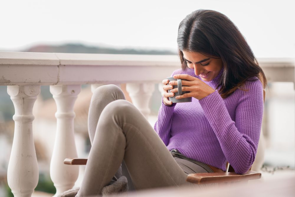 Female laughing outside on patio with a cosy warm drink