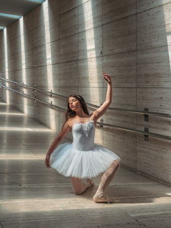Ballerina doing ballet posing at rail in classroom