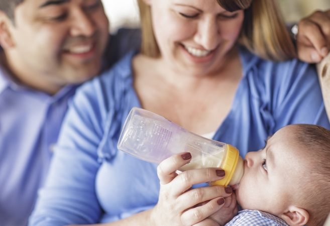 Happy Couple Bottle Feeding Their Son
