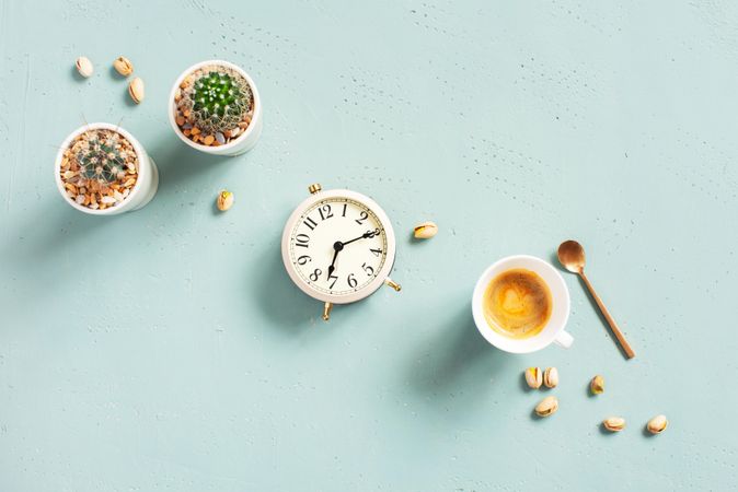 Espresso with spoon, with succulents and clock on baby blue background