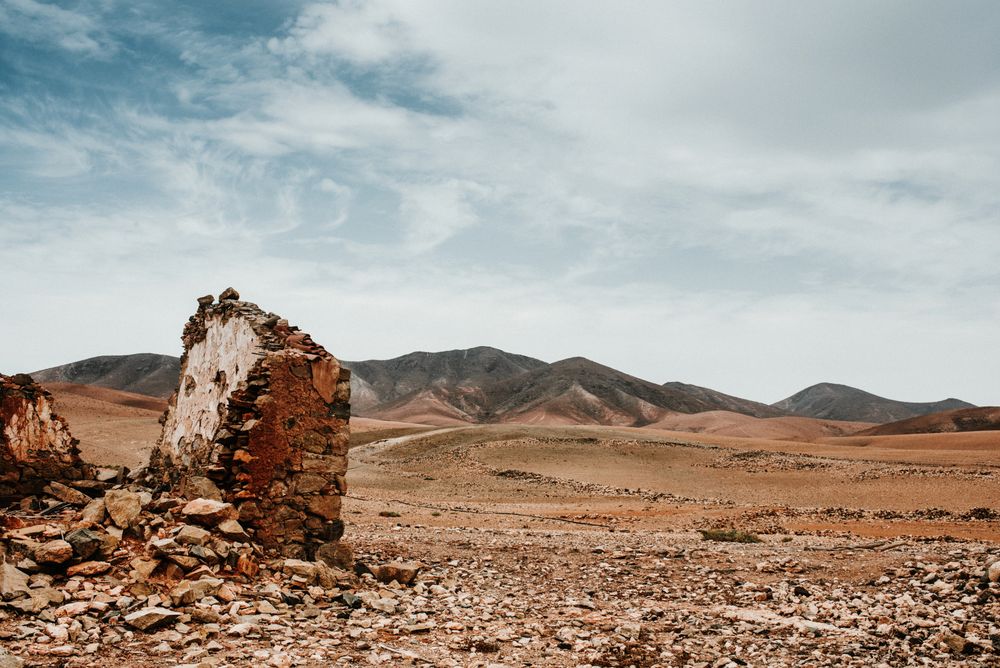 Dilapidated old buildings in mountain desert under cloudy sky