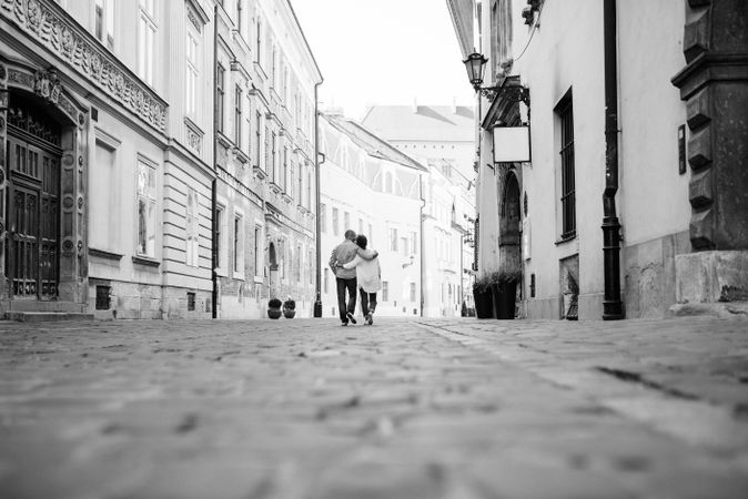 Grayscale photo of man and woman walking on street