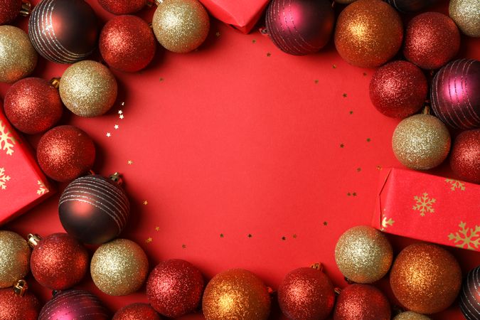 Christmas balls and presents on red background, space for text
