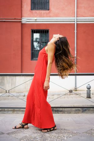 A Young Woman in a Beautiful Red Dress Posing Gracefully in a Serene Outdoor Setting