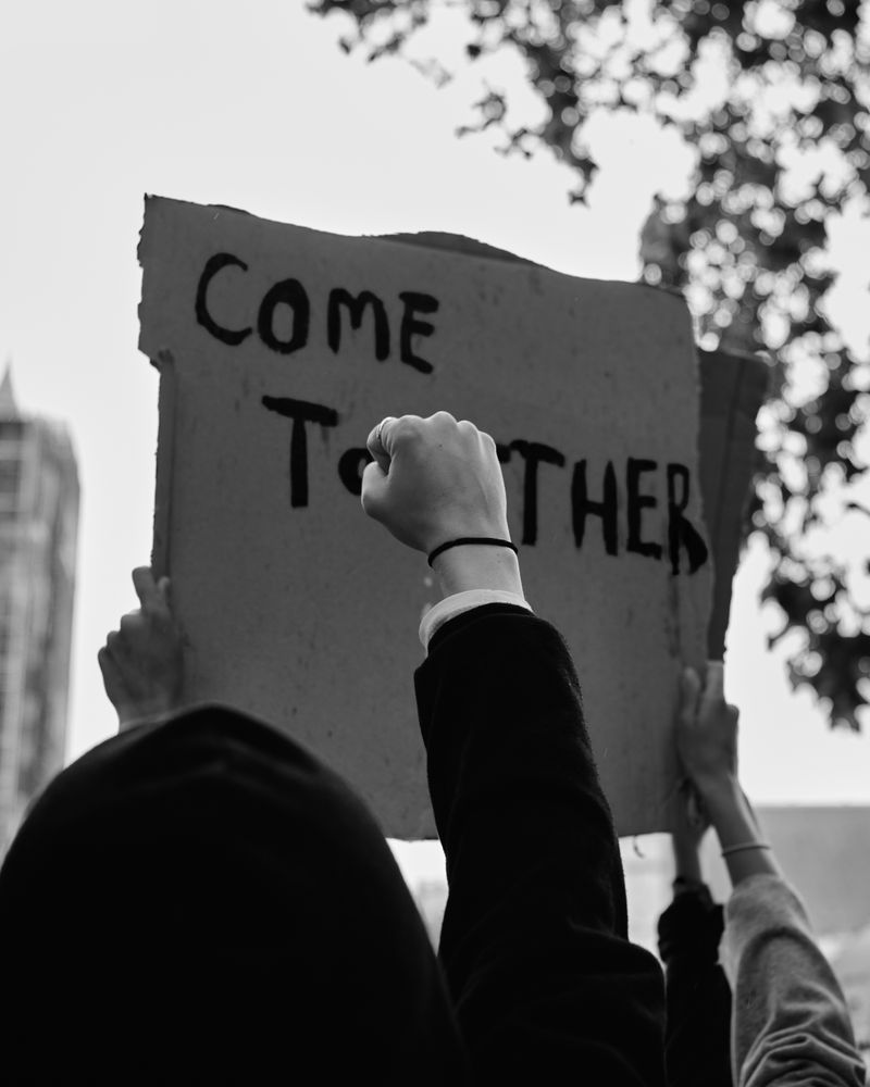 London, England, United Kingdom - June 6th, 2020: Raised fist in front of “Come Together” sign