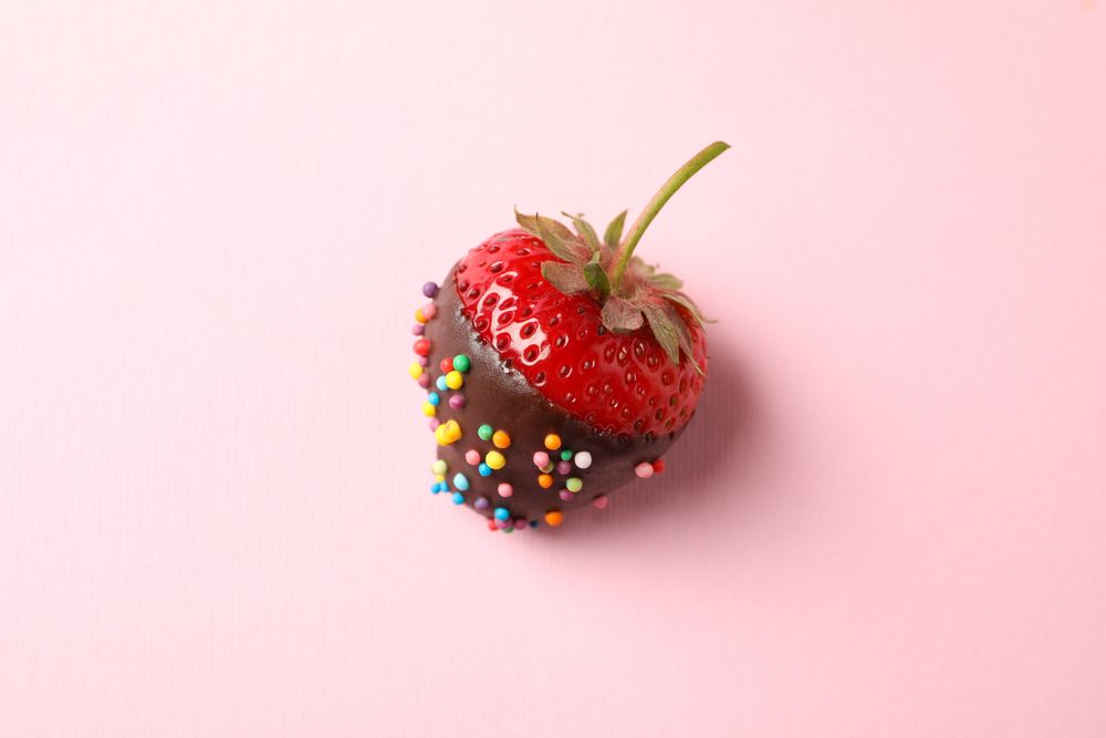 Chocolate fondue. Strawberry in chocolate on pink background