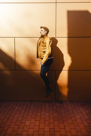 Confident guy jumping near modern wall