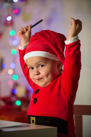 Cute kid in Santa costume with raised arms