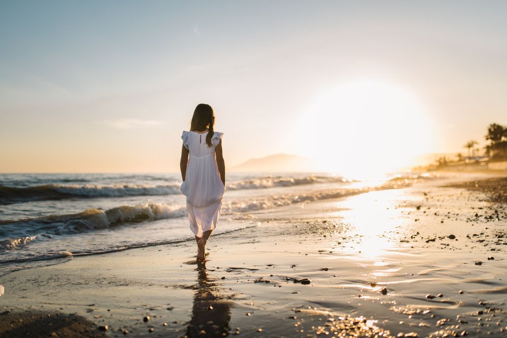 Adorable girl walking on seaside at sunset