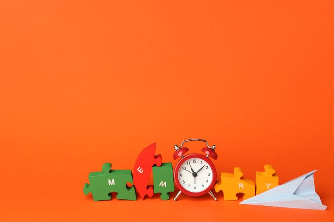 Puzzle pieces spelling “memory” in orange room with alarm clock and paper planes, copy space