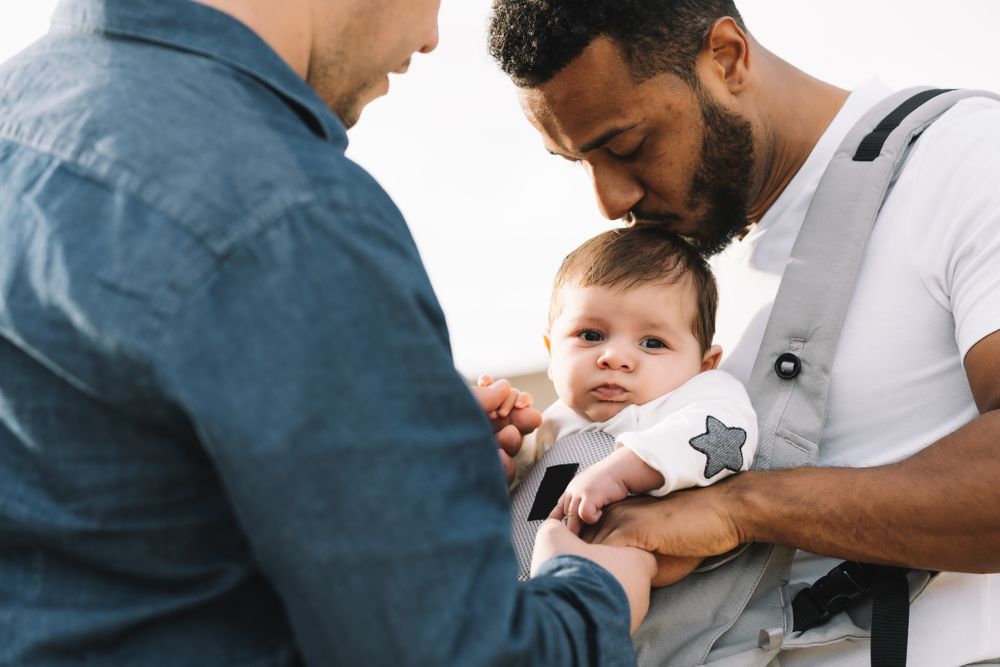 Unrecognizable diverse men walking with baby on nature