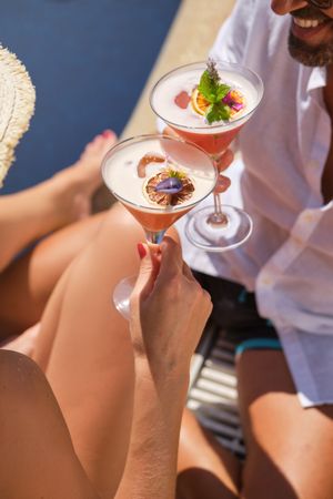 Crop couple clinking glasses of cocktail during holiday
