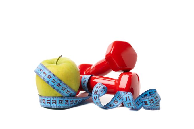 Dumbbells, apple and measuring tape isolated on blank background