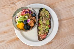 Tasty toast with avocado and salmon with fruit bowl