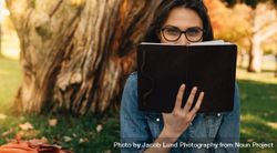 Woman peeking over a book in hand 4Z38Ab