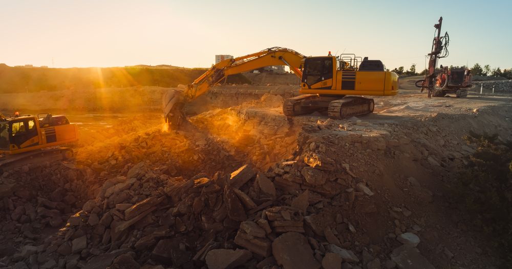 Aerial Drone Shot Of Construction Site On Sunny Day: Industrial Excavators Digging Rocks To Lay Foundation For A New Apartment Building. People Using Heavy Machinery To Complete A Real Estate Project.