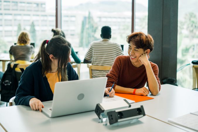 Diverse students sitting at table with laptop