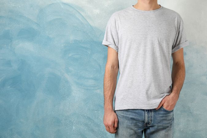 Men in blank grey t-shirt against blue background, space for text