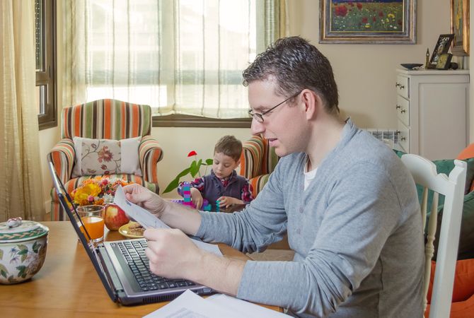 Father working in home office and son playing