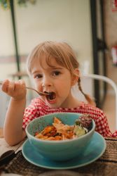 Girl eating with hand from blue bowl