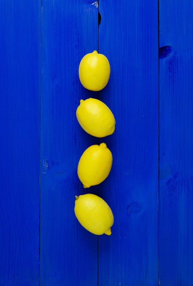 Four lemons stacked in the center on wood painted blue