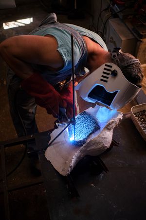 Craftsman in uniform in process of welding in garage