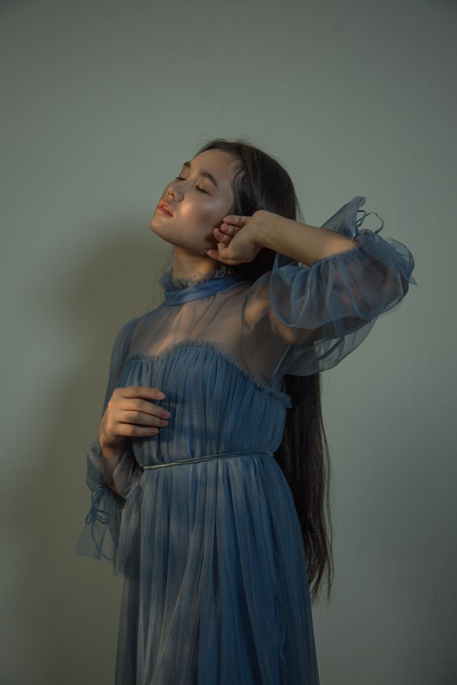 Woman in blue dress leaning on wall