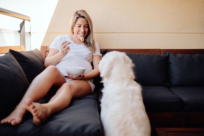 Smiling pregnant woman chilling with dog