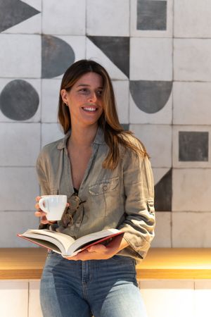 Dreamy woman with book and coffee in cafe