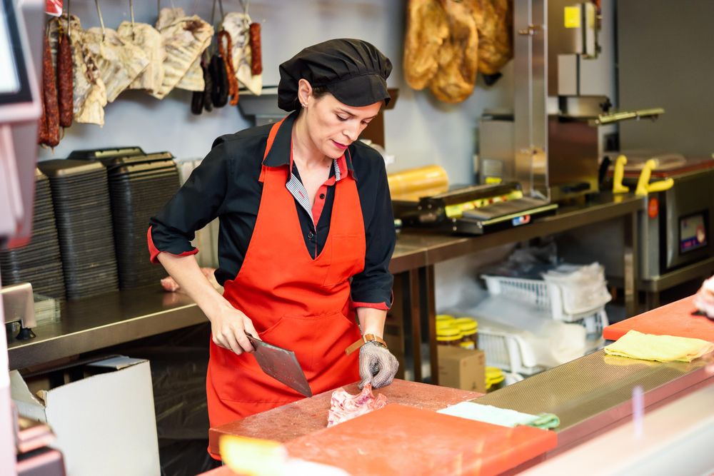 Woman in butcher shop cutting meat