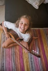 Lovely innocent girl playing acoustic guitar on floor