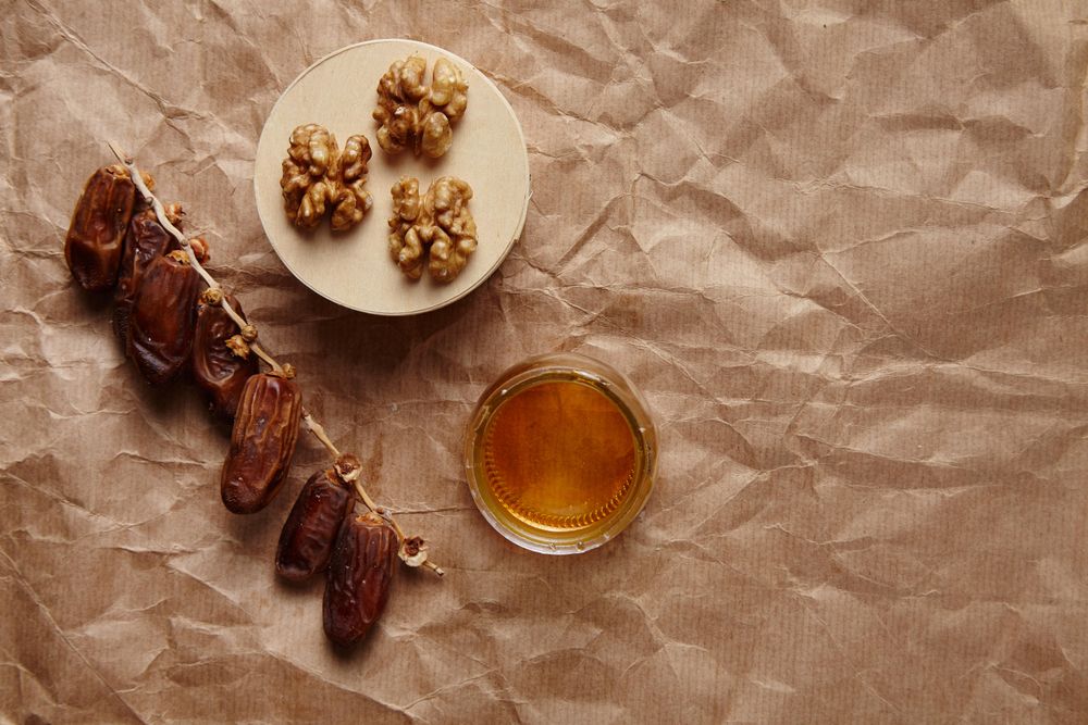 Top view of walnuts, honey and dates